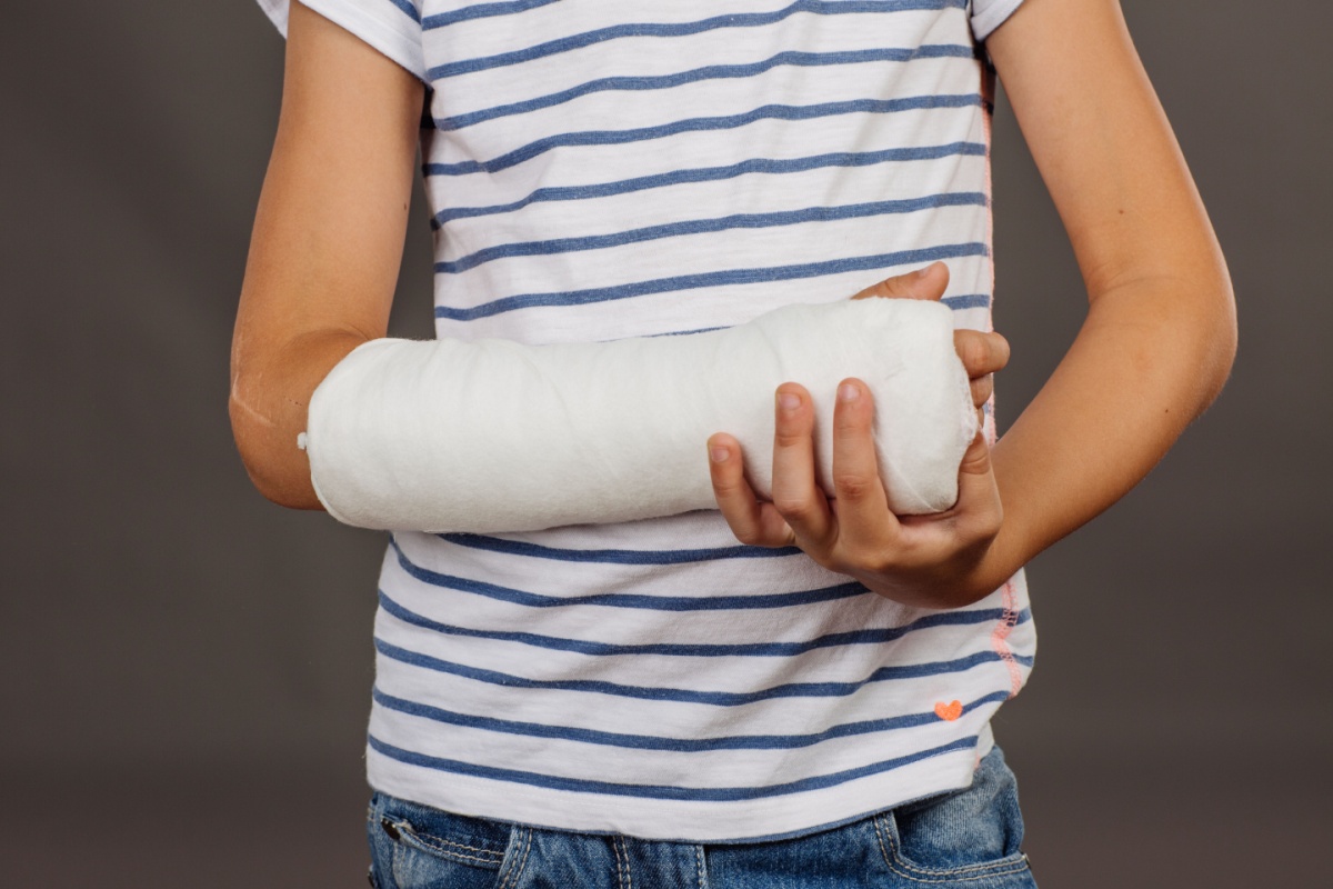 young boy cradling his broken arm, which is in a cast