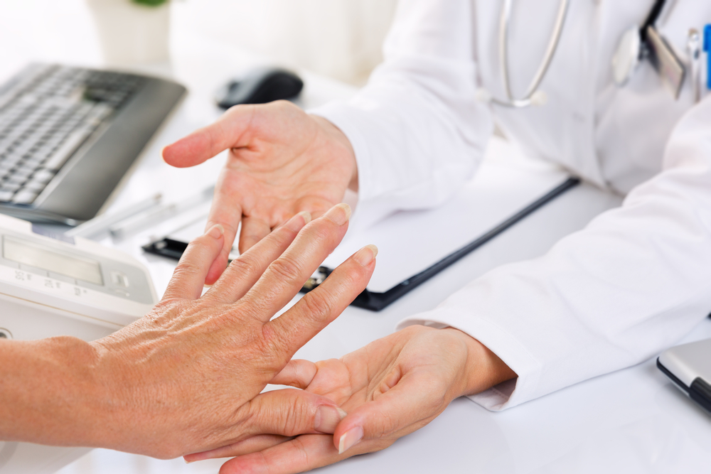 Elderly woman showing her hand to a doctor, who is looking for signs of rheumatoid arthritis