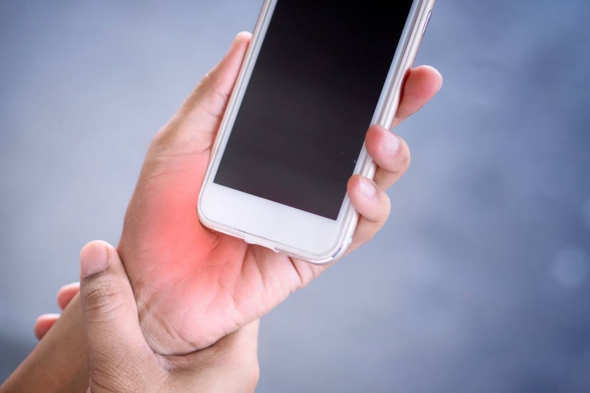 woman rubbing her wrist as she holds her smartphone