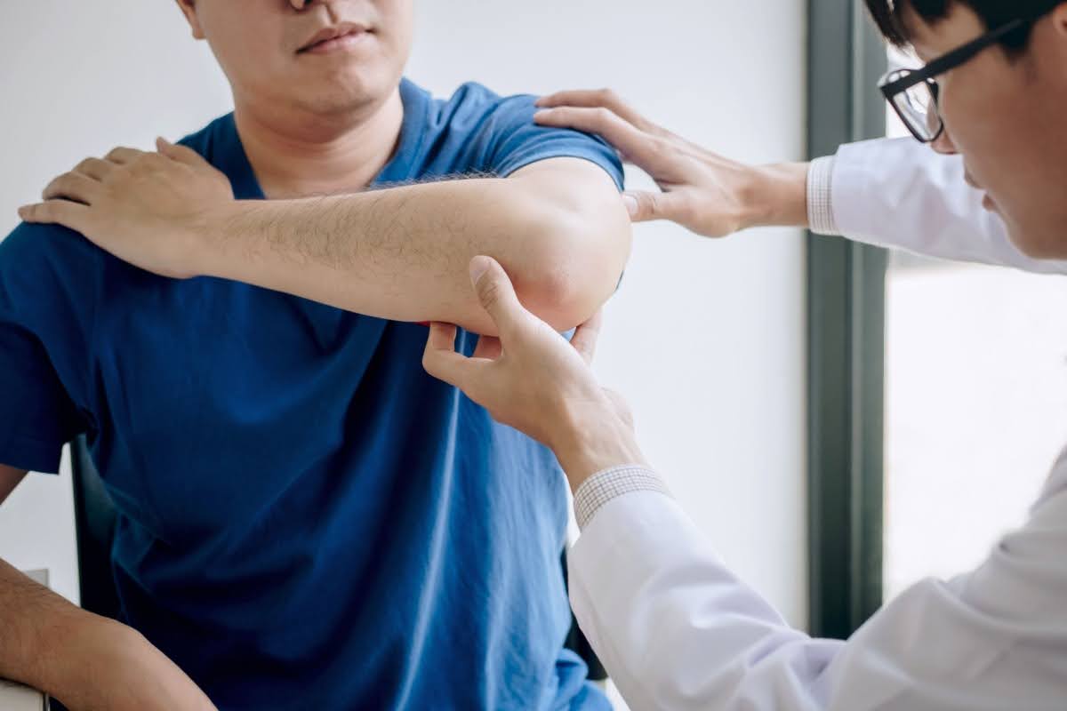 middle-aged man having his elbow inspected by a doctor